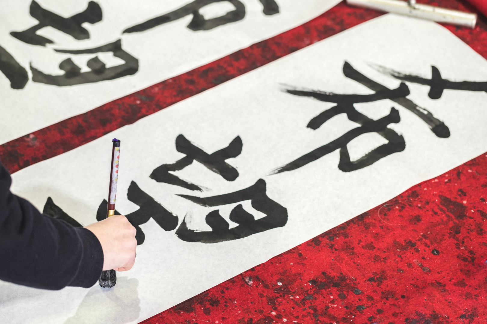 Mit einem Pinsel werden Kanji auf ein Papier gezeichnet