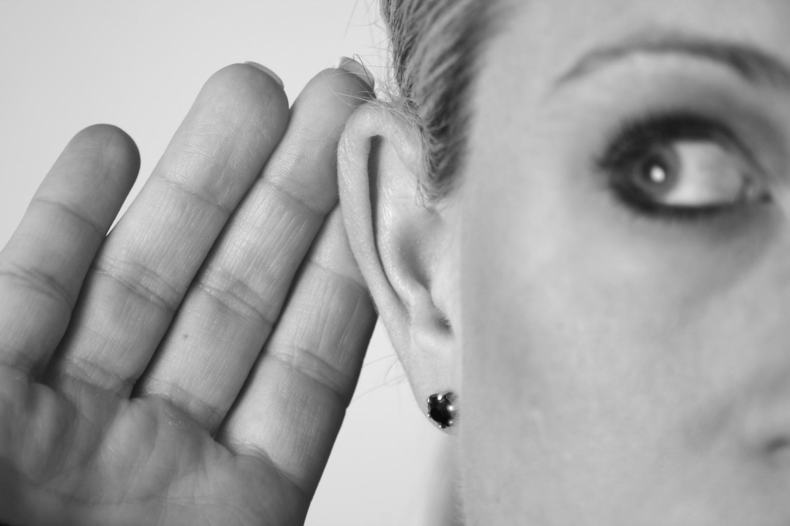 Eine Frau hält sich ihre Hand ans Ohr um besser zu verstehen